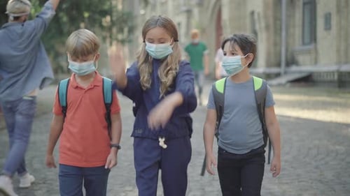 Middle School Pupils Strolling in Sunlight Outdoors with Elder Students Walking at the Background
