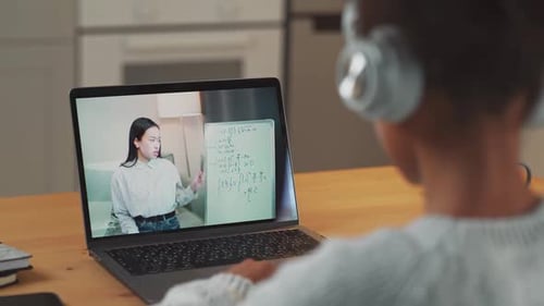 Child Learns Remotely with Laptop and Instructor