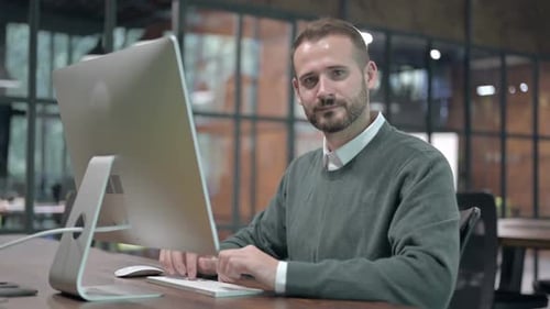 Bearded Man Working on Computer Giving Thumbs Up