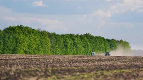 Two Tractors Plow the Field in the Spring Preparation for Sowing