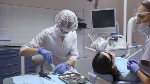 Zahnarzt und Assistentin bereiten sich auf die Operation vor, weiße Kittel und Masken, Krankenhauscomputer