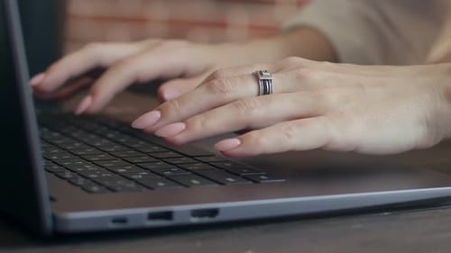 Woman Closeup Prints with Fingers on the Keyboard of Laptop at an Office Table