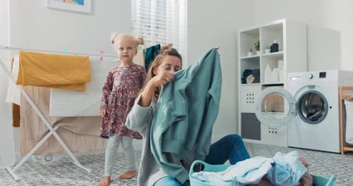 Mother and Daughter Folding Clothes in Laundry Room