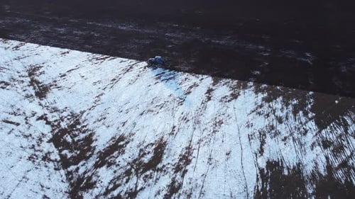 Vue aérienne de la terre enneigée cultivée par tracteur