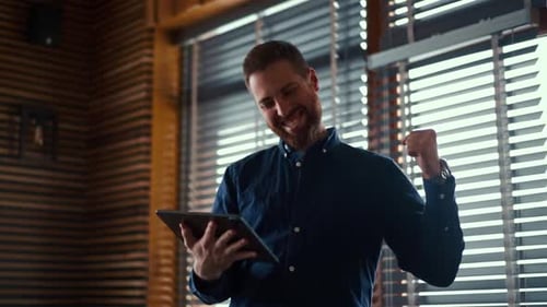 Excited Man Using Tablet in Modern Home