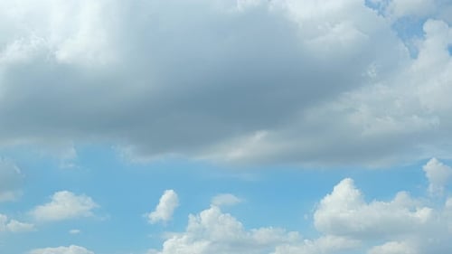 Fluffy White Clouds Float in Blue Sky