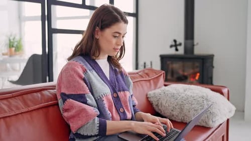 Young Woman Uses Laptop On Couch at Home