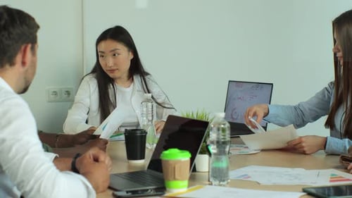 Young Adults in Office Meeting Discussing Graphs