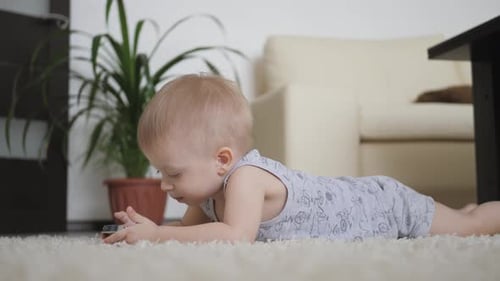 Cute Child Lying on Rug Looking at Phone