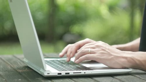 Hands Typing on Laptop Computer Outdoors