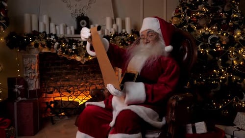 Santa Claus Reading the Scroll by the Fireplace