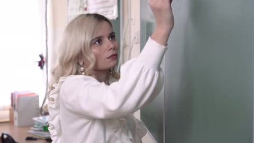 Beautiful School Physics Teacher Writes a Formula with Chalk on a School Board