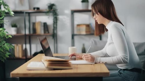 Woman Studies with Laptop and Notebook at Desk
