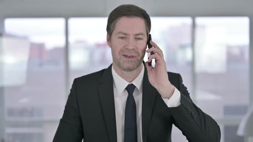 Middle Aged Businessman Talking on Smartphone in Office