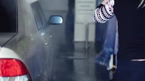 Woman Washing Car with Pressure Washer in Carwash