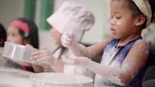 Gruppe von Kindern, die gemeinsam Kuchen im Klassenzimmer backen, multiethnische Jungen und Mädchen machen glücklich beim Backen.