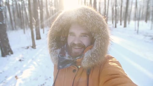 Smiling Man in Snowy Winter Forest with Furry Hood