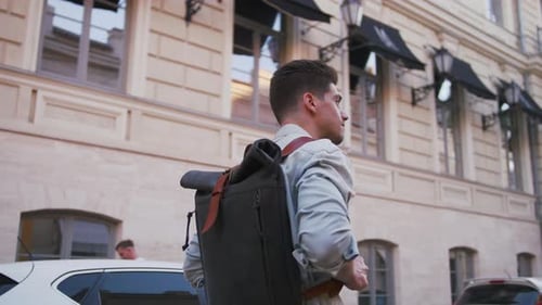 Attractive Young Handsome Man Tourist with Backpack Walking in City Center and Looking Around