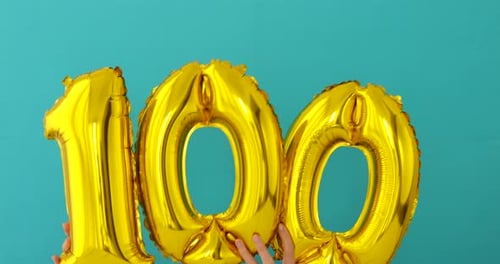 Gold Number Balloons spelling 100 Held by Hands