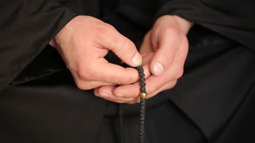 Mann betet mit Rosenkranz