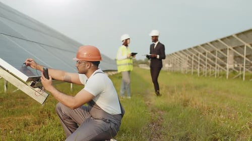 Energietechniker in Helm und Uniform mit Multimeter zur Spannungsmessung