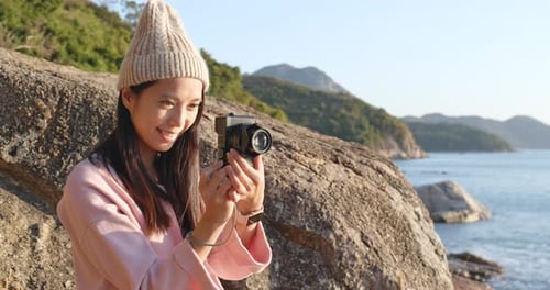 Young Woman Taking Photos on Rocky Coastline