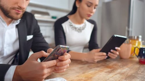 Man and Woman Using Digital Devices in Kitchen