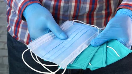 Gloved Hands Holding Disposable Colorful Face Masks