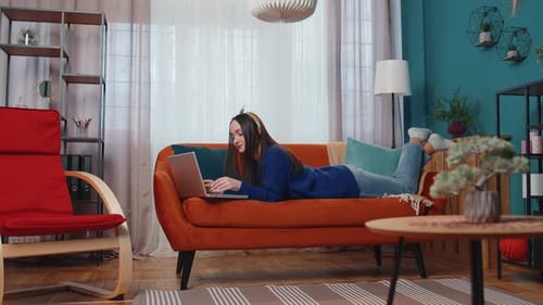 Woman Lying on Couch Typing on Laptop