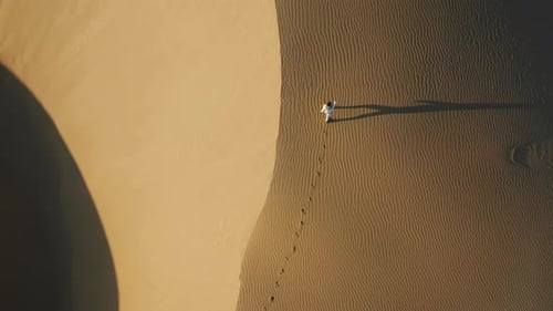 Aerial View of the Woman Walking By Sand Dunes in the Desert Nature