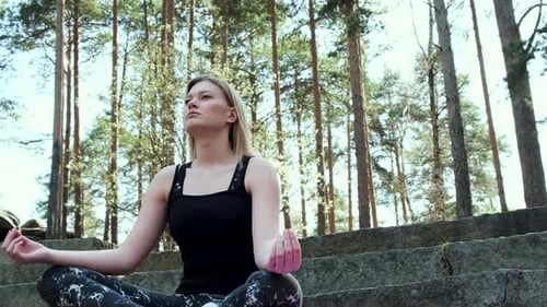 Young Woman Meditating in Forest Setting