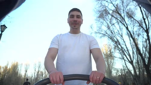 A Young Father Walks with a Baby in a Stroller in the Park