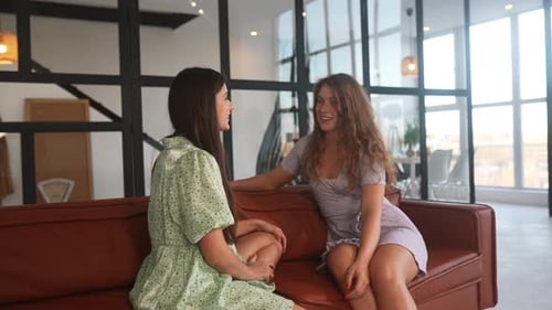 Two Women Talking on Modern Sofa Indoors