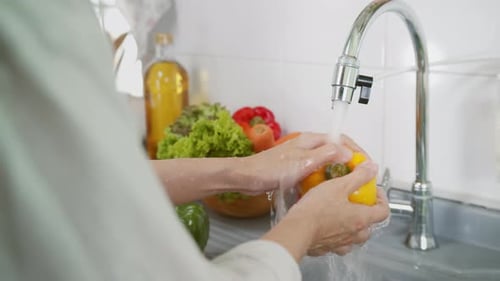 Close up of Woman Hand Tap water Washing a Fresh Organic Bell Pepper