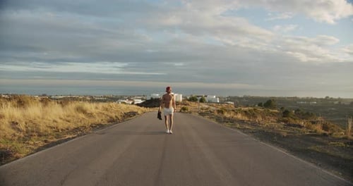 Shirtless Man In Shorts Walking Empty Road