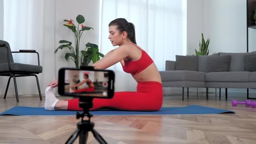 Young Woman Stretching and Recording with Smartphone