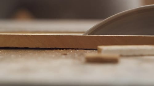 Iron circular saw slowly divides a marble tile and fragments fly from it in different directions