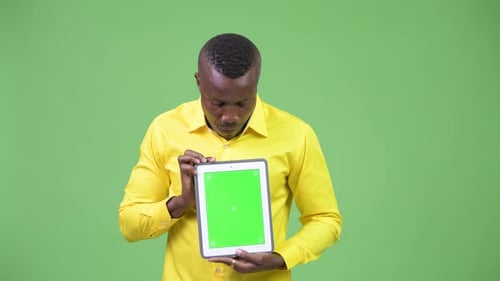 Man Holds Tablet with Green Screen, Looks Surprised