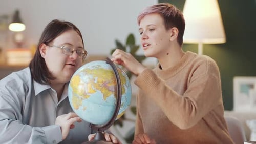Man with Down Syndrome Learning World Map on Globe with Teacher
