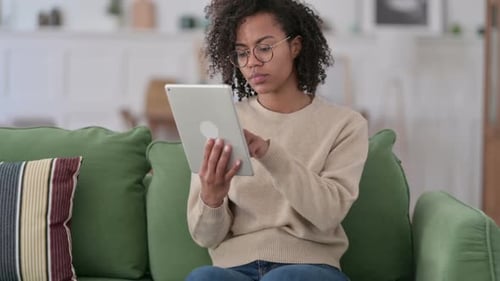 Young Woman Uses Tablet on Green Sofa Indoors