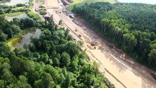 Construction of a new road through city park. Mining dump trucks. Drone footage