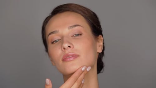 Elegant Woman Applying Skincare Serum and Lotion