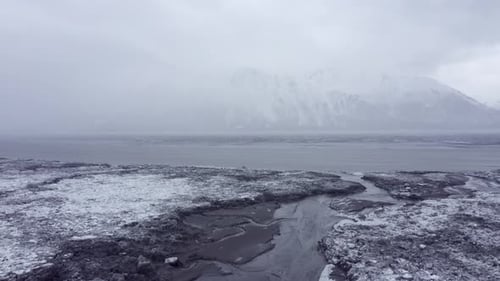 Aerial View of Snowy Streams and Misty Mountains