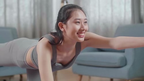 Junge asiatische athletische Frau in Sportkleidung macht Yoga im Balancing Table Pose auf der Matte zu Hause
