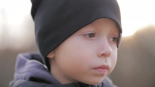 Contemplative Child Wearing a Black Beanie Outdoors