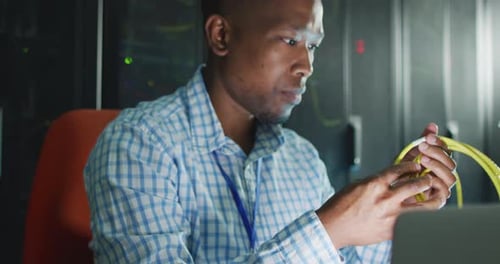 Afroamerikanischer männlicher Computertechniker, Laptop, der im Business-Serverraum arbeitet