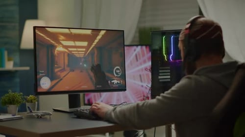 Young Adult Playing Futuristic Video Game at Computer