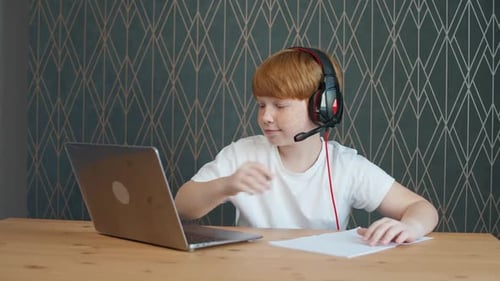 Boy Doing Homework with Laptop and Headphones