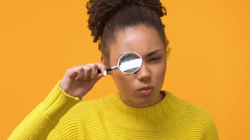 Femme africaine sérieuse regardant à travers la loupe, détective, recherche