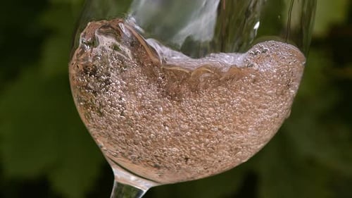 Vino rosado que se vierte en el vaso, cámara lenta